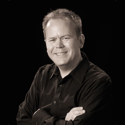 Headshot of Mark on a black background.